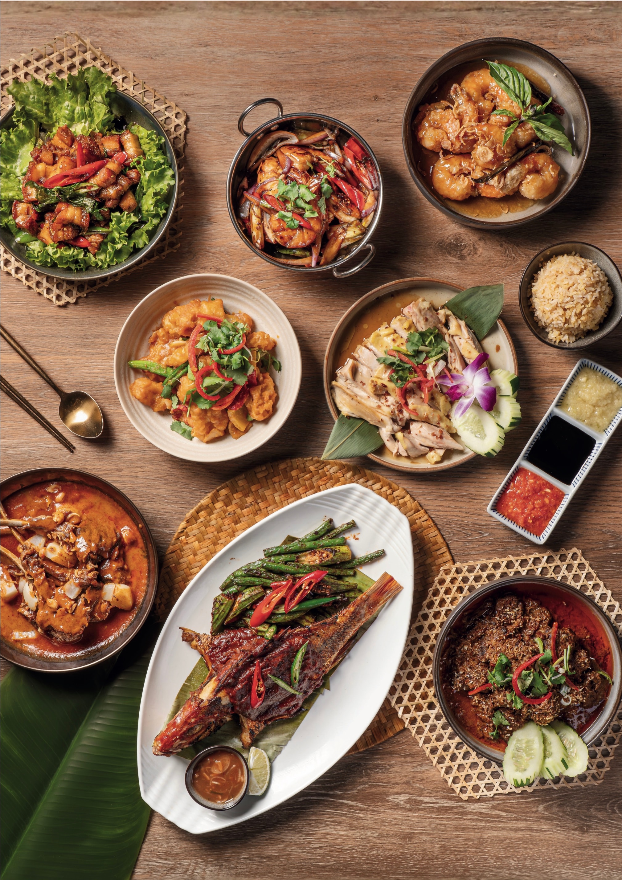 A full table of chef's specials: whole fish, curries, greens and rice